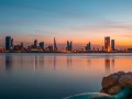 Manama skyline at sunset reflected on the water, Bahrain
