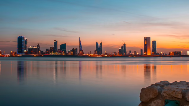 Manama skyline at sunset reflected on the water, Bahrain